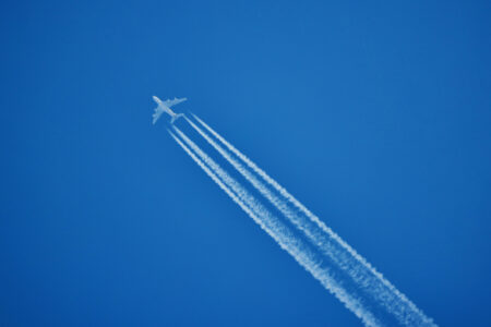 an airplane and the traces it leaves on a blue sky.